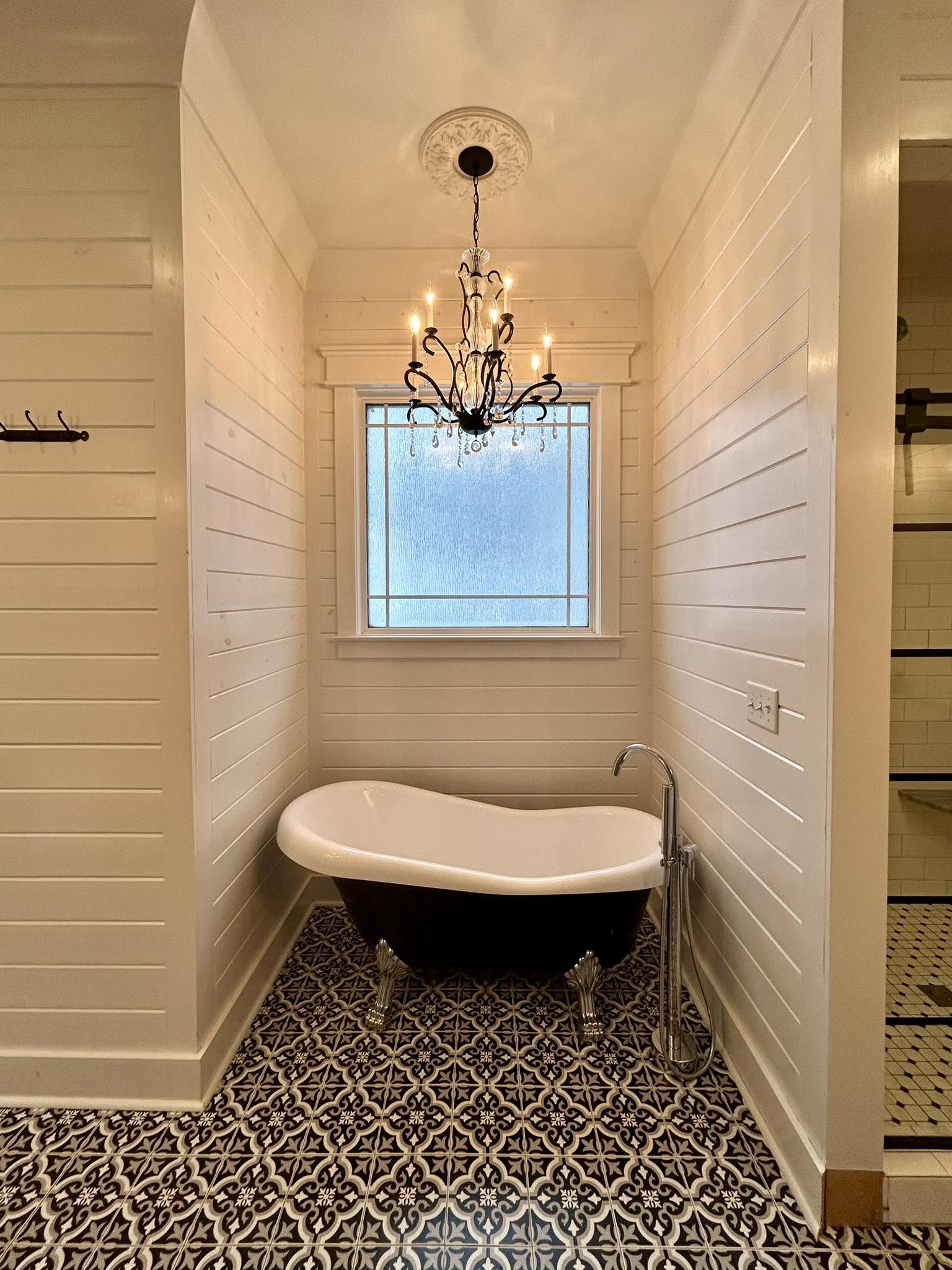 A freshly cleaned cottage bathroom with a clawfoot tub and patterned tile