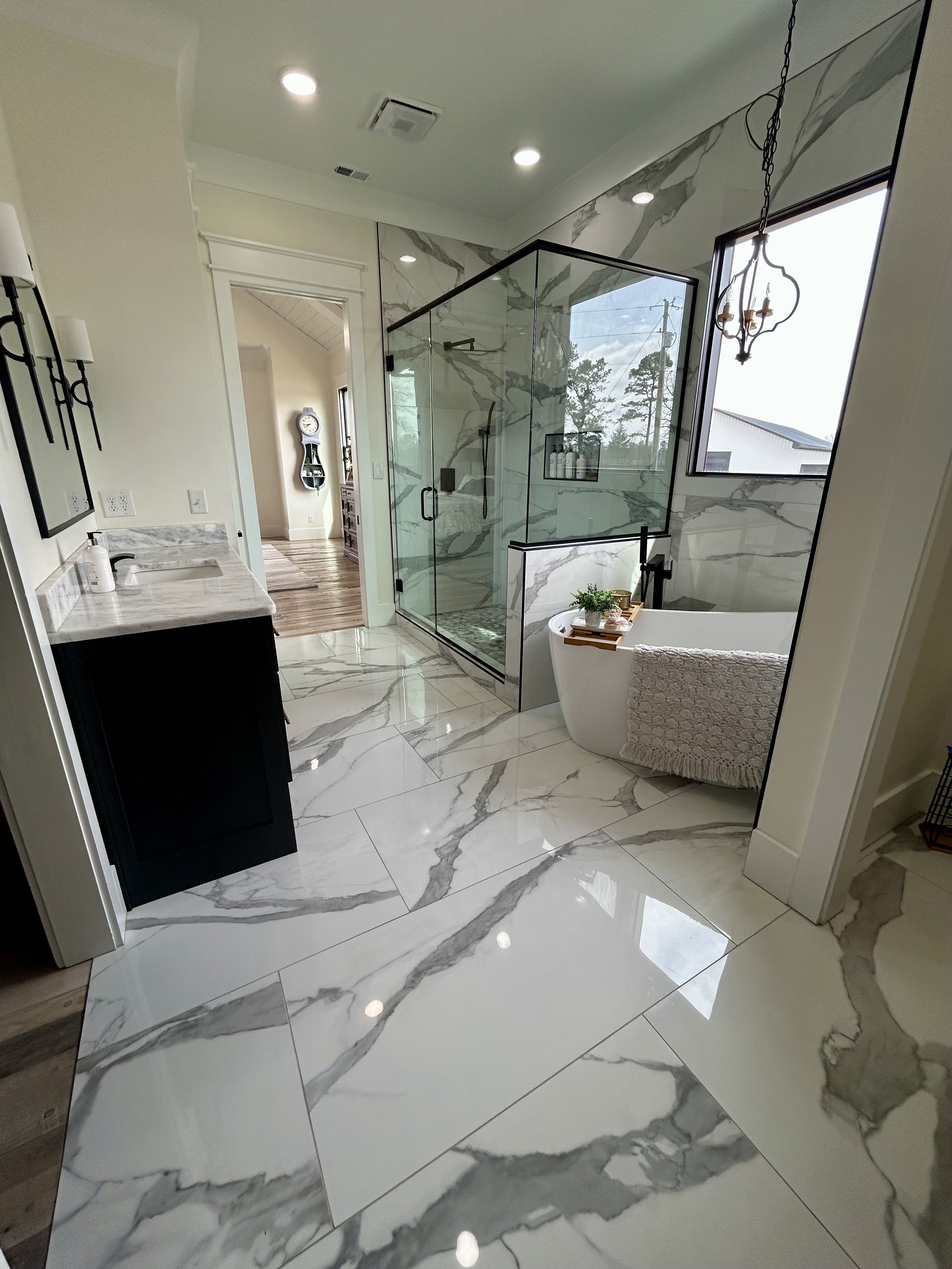 A luxurious, freshly cleaned marble bathroom with a freestanding tub and glass shower